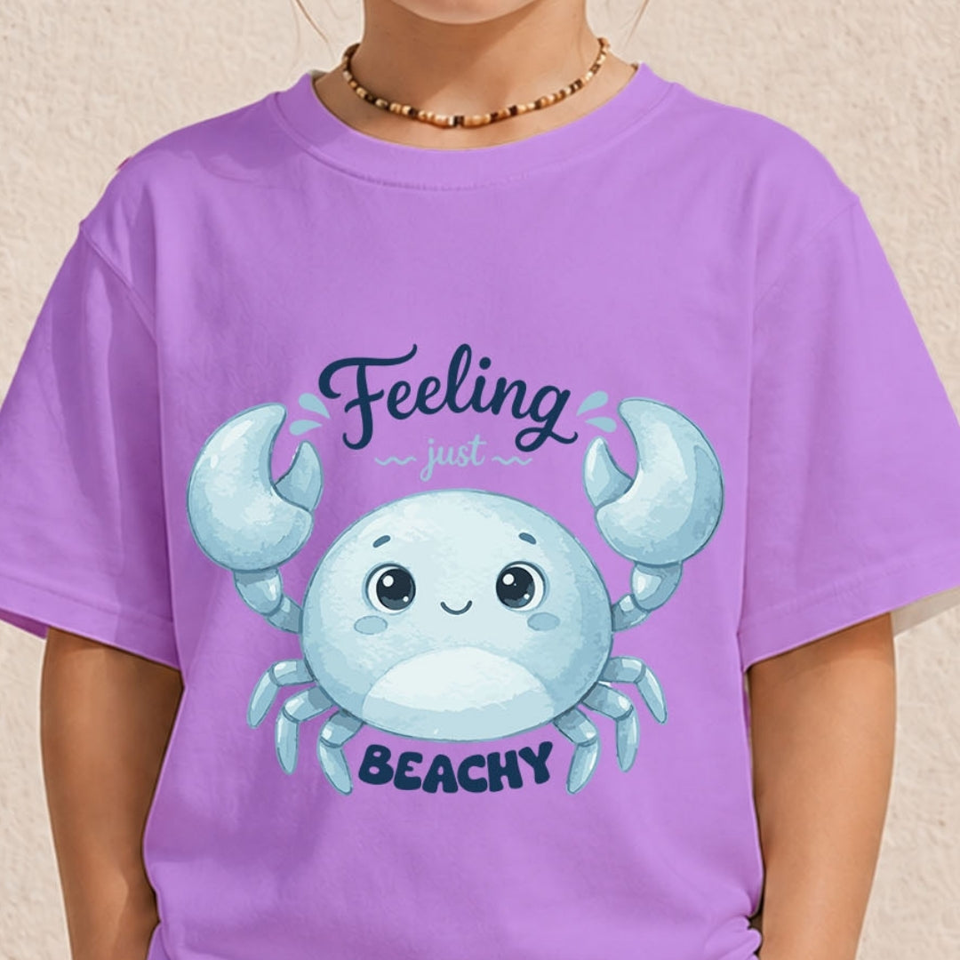 A person wearing a purple t-shirt featuring a blue cartoon crab graphic and the text "Feeling just BEACHY".