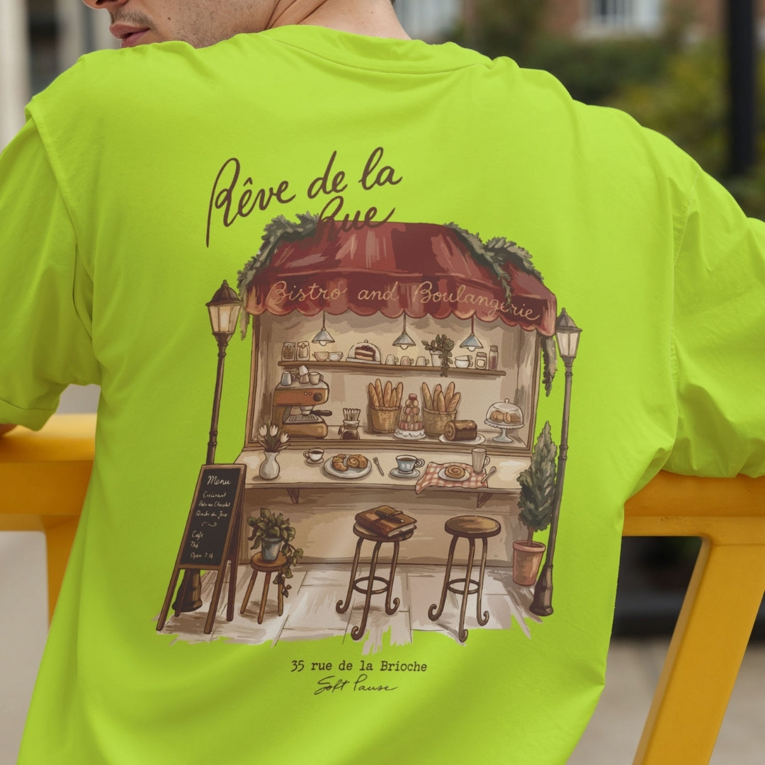 Back view of a person wearing a bright lime green t-shirt showcasing the detailed French bakery stall illustration with the text "Rêve de la Rue".