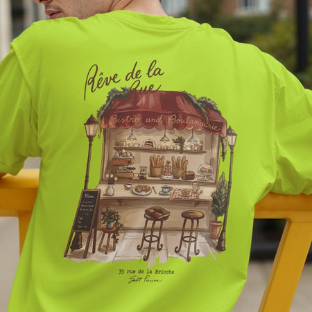 Back view of a person wearing a bright lime green t-shirt showcasing the detailed French bakery stall illustration with the text "Rêve de la Rue".