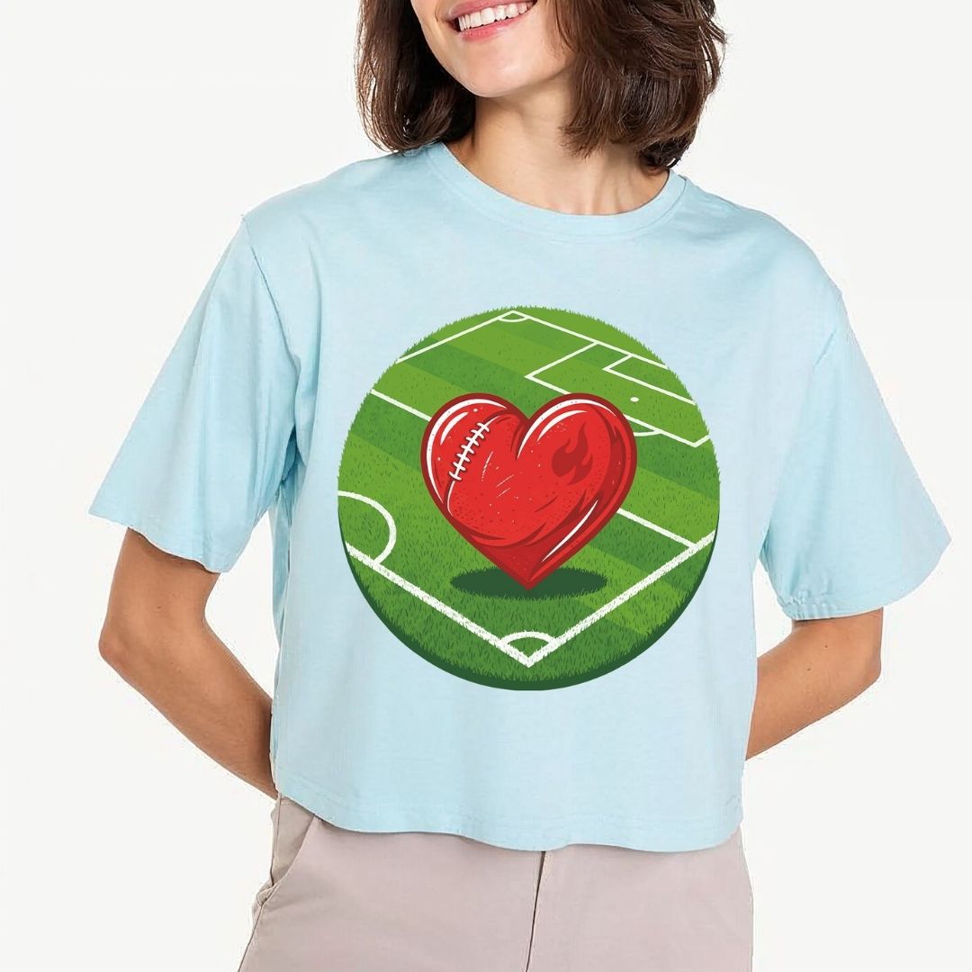 Person wearing a light blue t-shirt with a red heart and football field design on a white background
