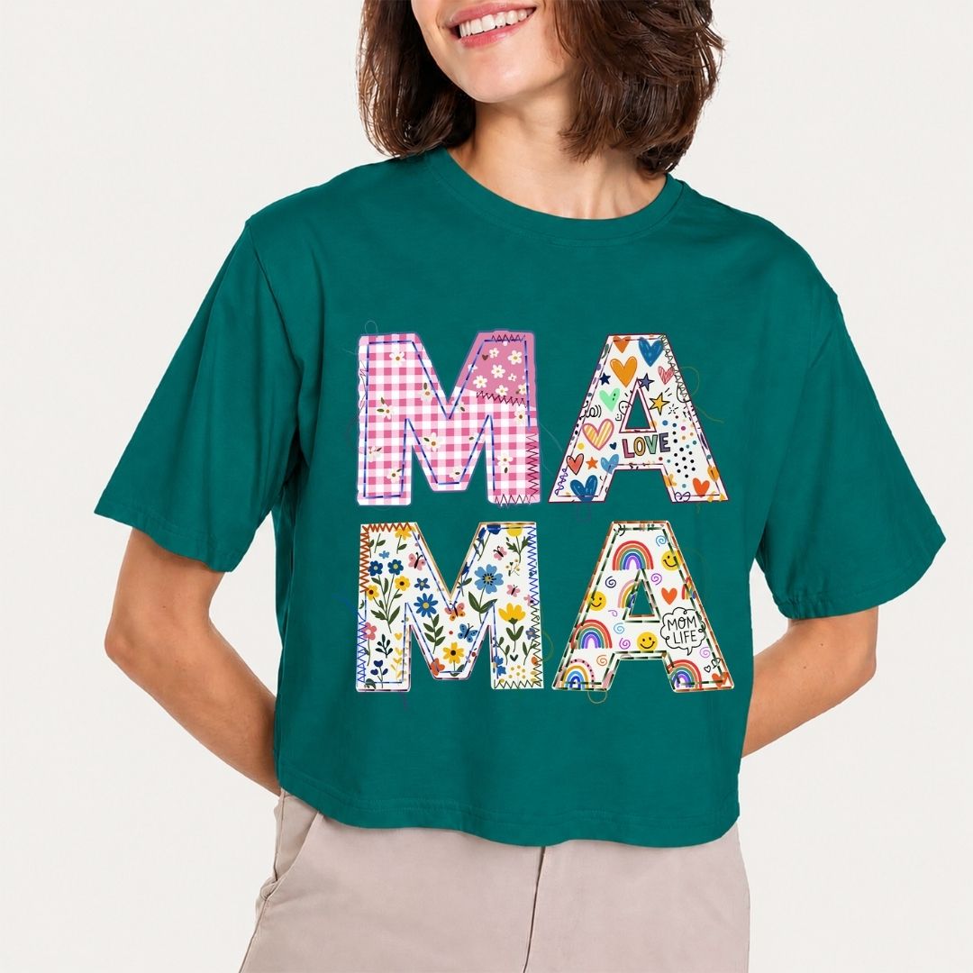 Person wearing a teal t-shirt with colorful 'MAMA' design on a plain background