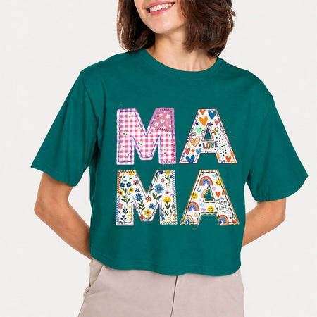 Person wearing a teal t-shirt with colorful 'MAMA' design on a plain background