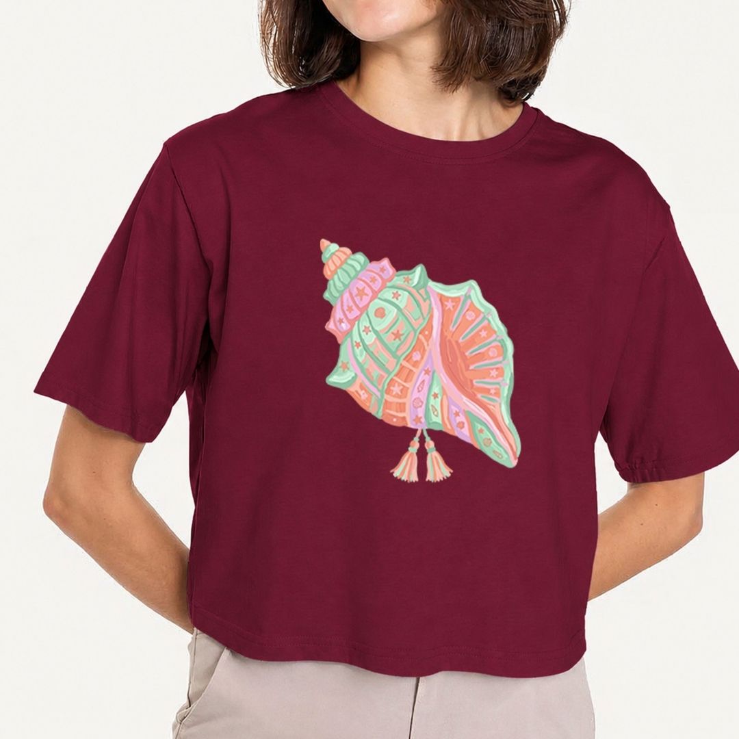 Person wearing a maroon t-shirt with a colorful shell design on a plain background
