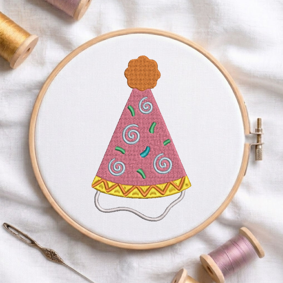 Pink birthday hat embroidery design with swirls and squiggles displayed in a wooden embroidery hoop.