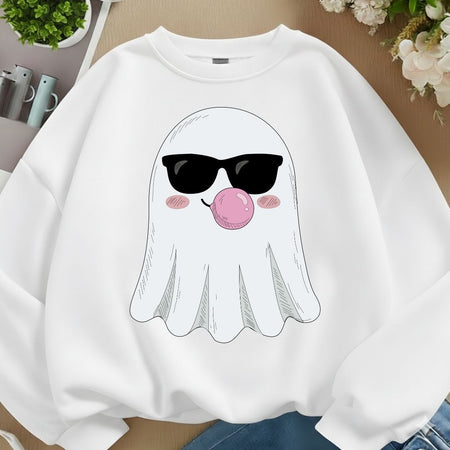 A white crewneck sweatshirt featuring a cartoon ghost graphic wearing black sunglasses and blowing a pink bubblegum bubble, displayed on a wooden surface with lifestyle props.