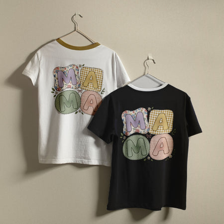 White and black t-shirts hanging on a wall, both displaying the pastel patchwork "MAMA" graphic printed on the back.