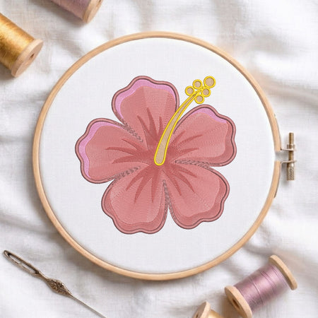 A circular embroidery hoop holding white fabric with a stitched pink hibiscus flower design outlined in brown, surrounded by spools of thread and a needle on a white fabric background.