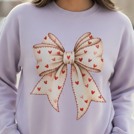 Light purple sweatshirt with a large bow design featuring small hearts on a blurred background