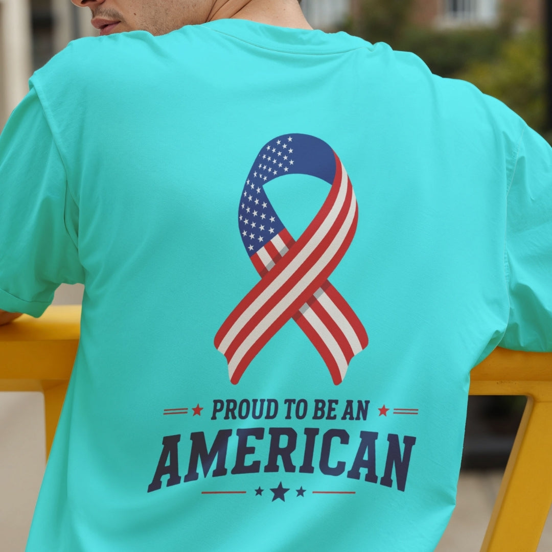A person seen from the back wearing a bright turquoise t-shirt featuring an American flag ribbon graphic and the text "Proud to be an American."