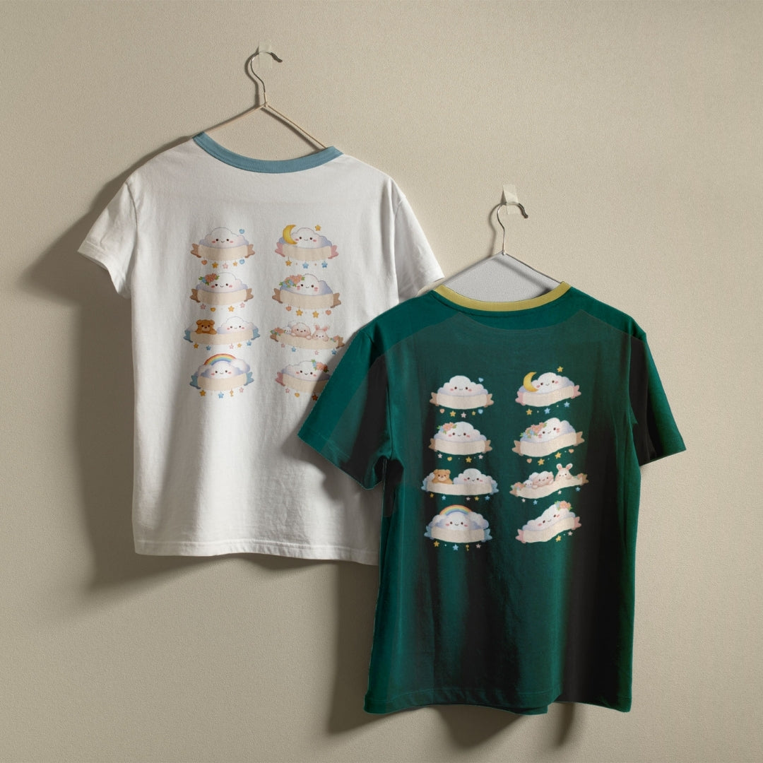 White and dark green t-shirts hanging on a wall, both displaying the eight kawaii cloud banner graphics on the back.