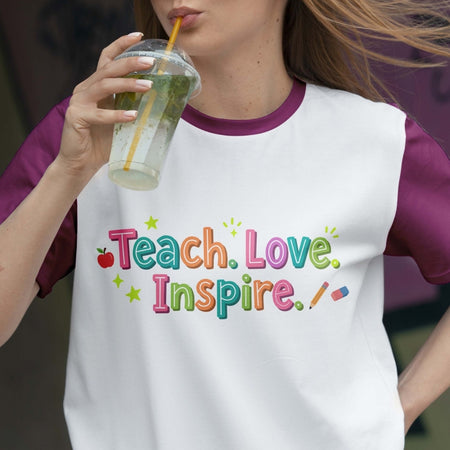 Person wearing a shirt with 'Teach. Love. Inspire.' text, holding a drink.