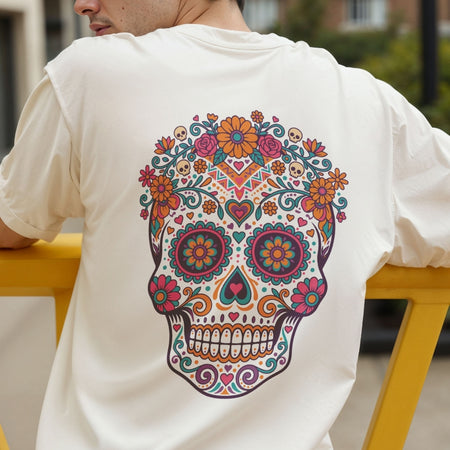 A person wearing a white short-sleeve T-shirt, shown from the back, featuring a large colorful sugar skull graphic with floral and geometric patterns.
