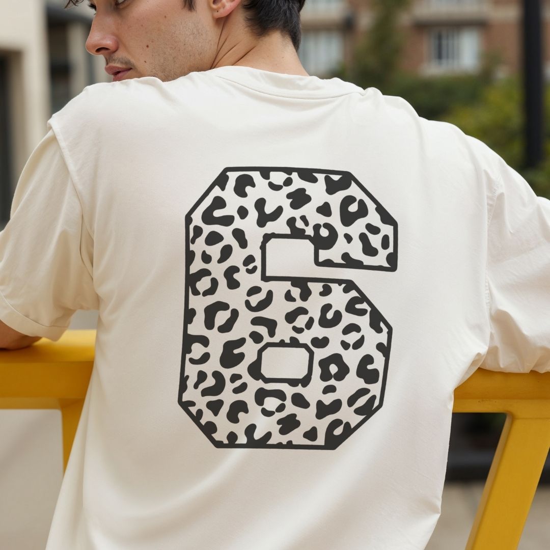 Person wearing a white t-shirt with a large number 6 in leopard print design.