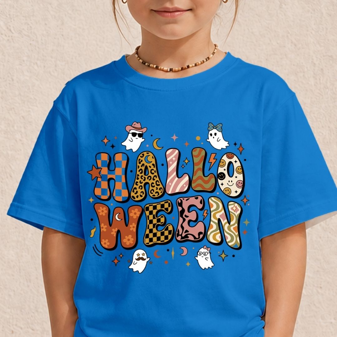 A child wearing a bright blue short-sleeve t-shirt with a colorful 'HALLOWEEN' graphic printed on the front, featuring cartoon ghosts, stars, and patterned letters, set against a neutral textured beige wall.