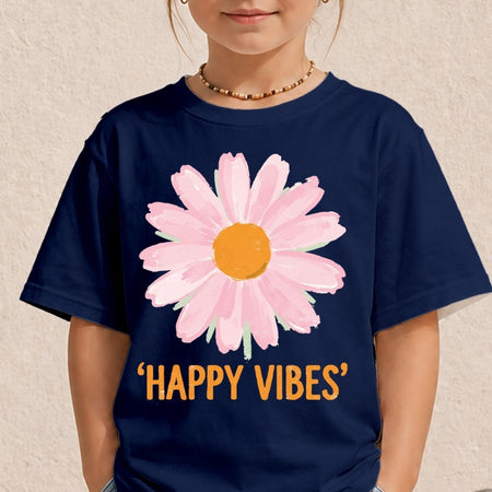 A child wearing a navy blue t-shirt with a large pink daisy graphic and the text 'HAPPY VIBES' in orange. The child is wearing a gold beaded necklace, and the background is a textured beige wall.