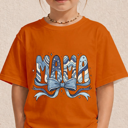 Close-up of a child wearing a bright orange t-shirt printed with a decorative blue and cream "MAMA" letter design topped with a large ribbon bow.