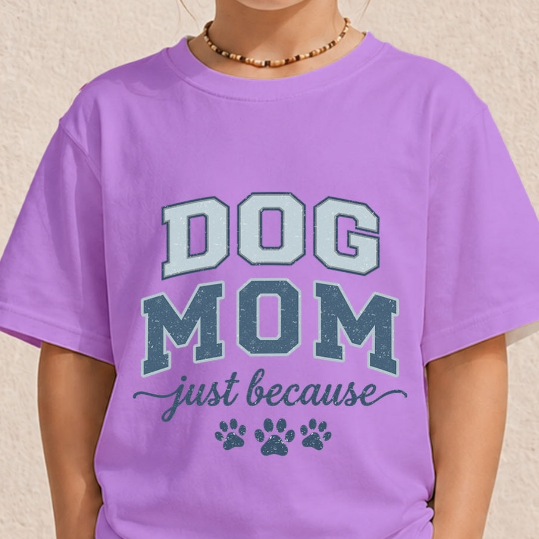 Close-up of a youth or toddler wearing a pastel lavender purple t-shirt printed with a vintage varsity-style "Dog Mom just because" design.