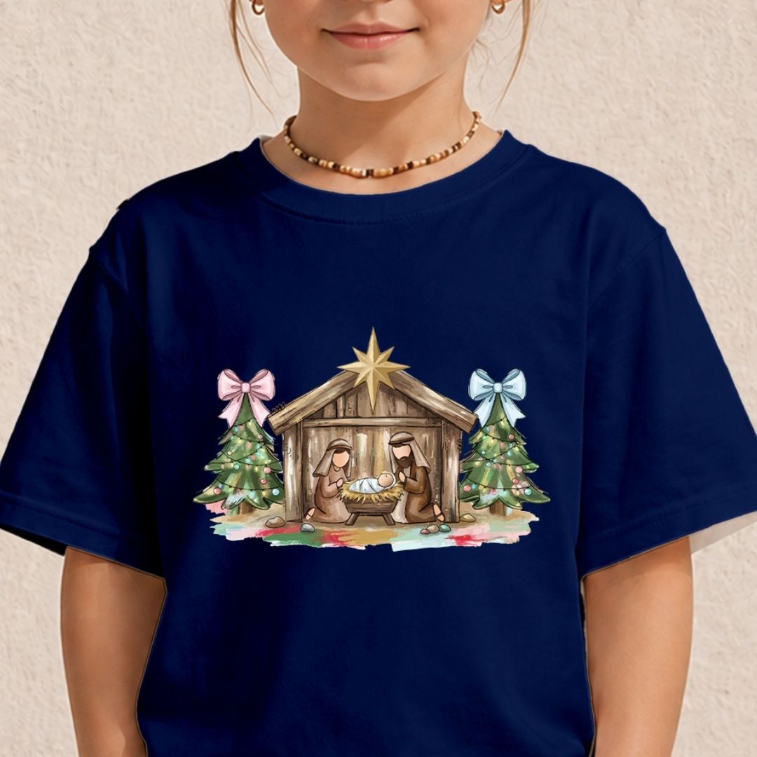 A child wearing a navy blue short-sleeve t-shirt with a colorful Christmas nativity scene graphic on the chest, set against a light beige textured wall.