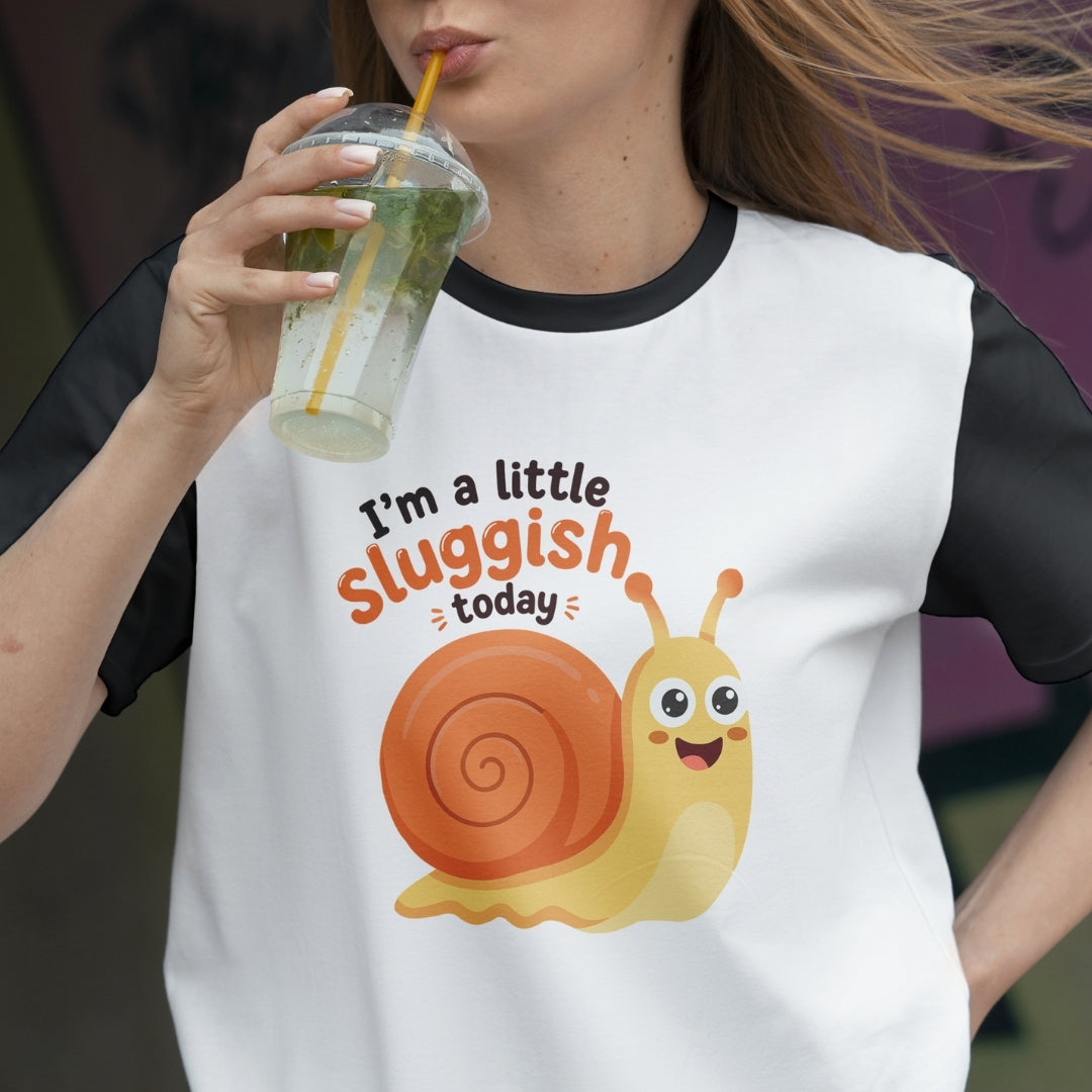 Person wearing a t-shirt with a snail graphic and text, holding a drink.