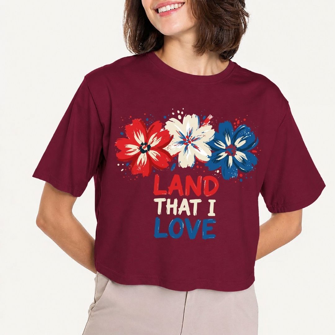 Person wearing a maroon t-shirt with floral design and 'LAND THAT I LOVE' text on a plain background