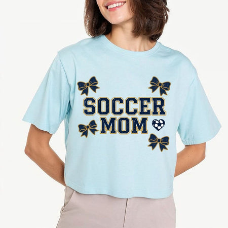 Light blue t-shirt with 'Soccer Mom' text and bow graphics worn by a person.