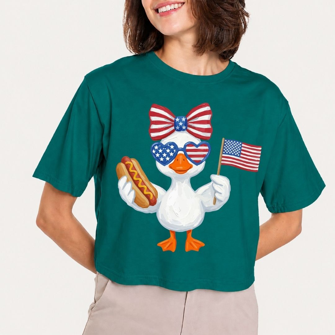 Person wearing a green t-shirt with a cartoon duck holding an American flag and a hot dog, on a plain background.