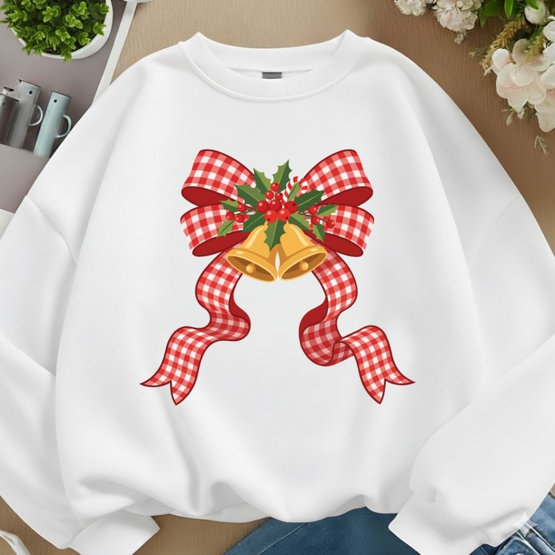 A white crewneck sweatshirt mockup featuring a large red-and-white gingham bow tied around golden Christmas bells and holly berries.