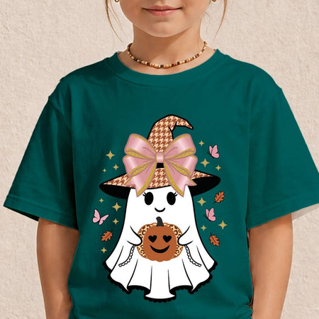 A child wearing a dark teal green t-shirt with a cartoon graphic of a cute ghost in a witch hat holding a pumpkin. The child is shown from the chin down, wearing a beaded necklace against a textured beige wall.