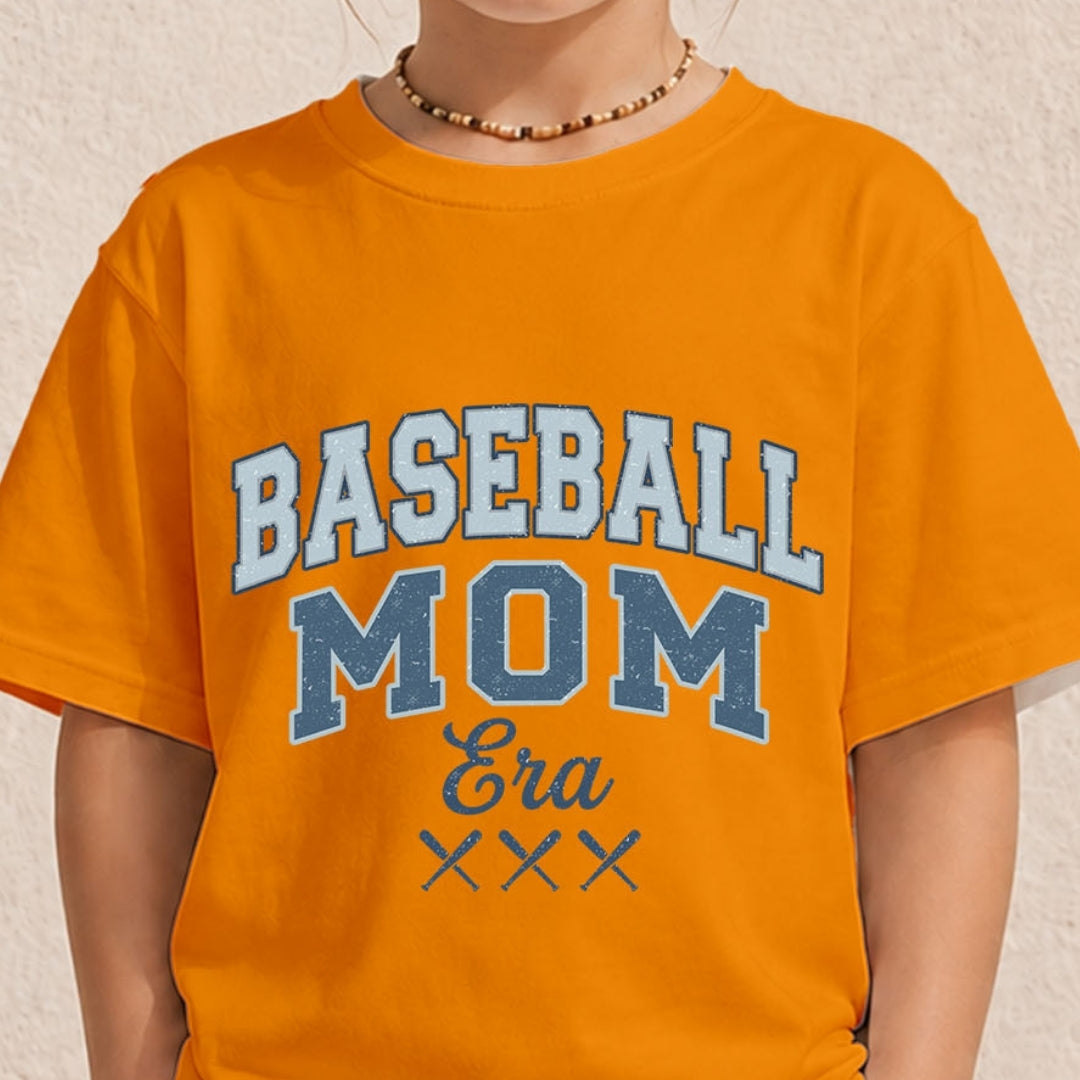 Close-up of a youth or toddler wearing a bright orange t-shirt printed with a vintage varsity-style "Baseball Mom Era" design.