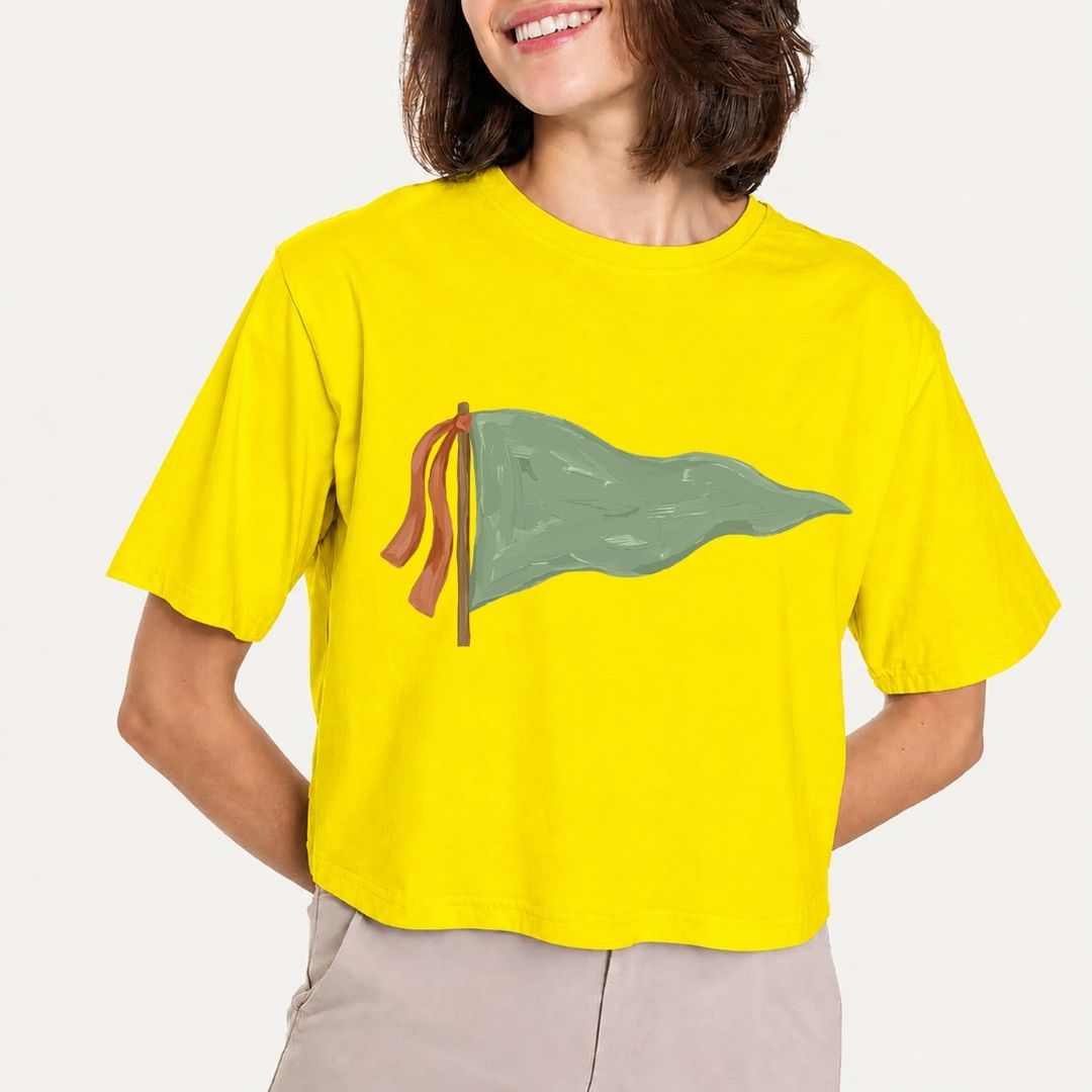 Person wearing a yellow t-shirt with a green flag design on a plain background