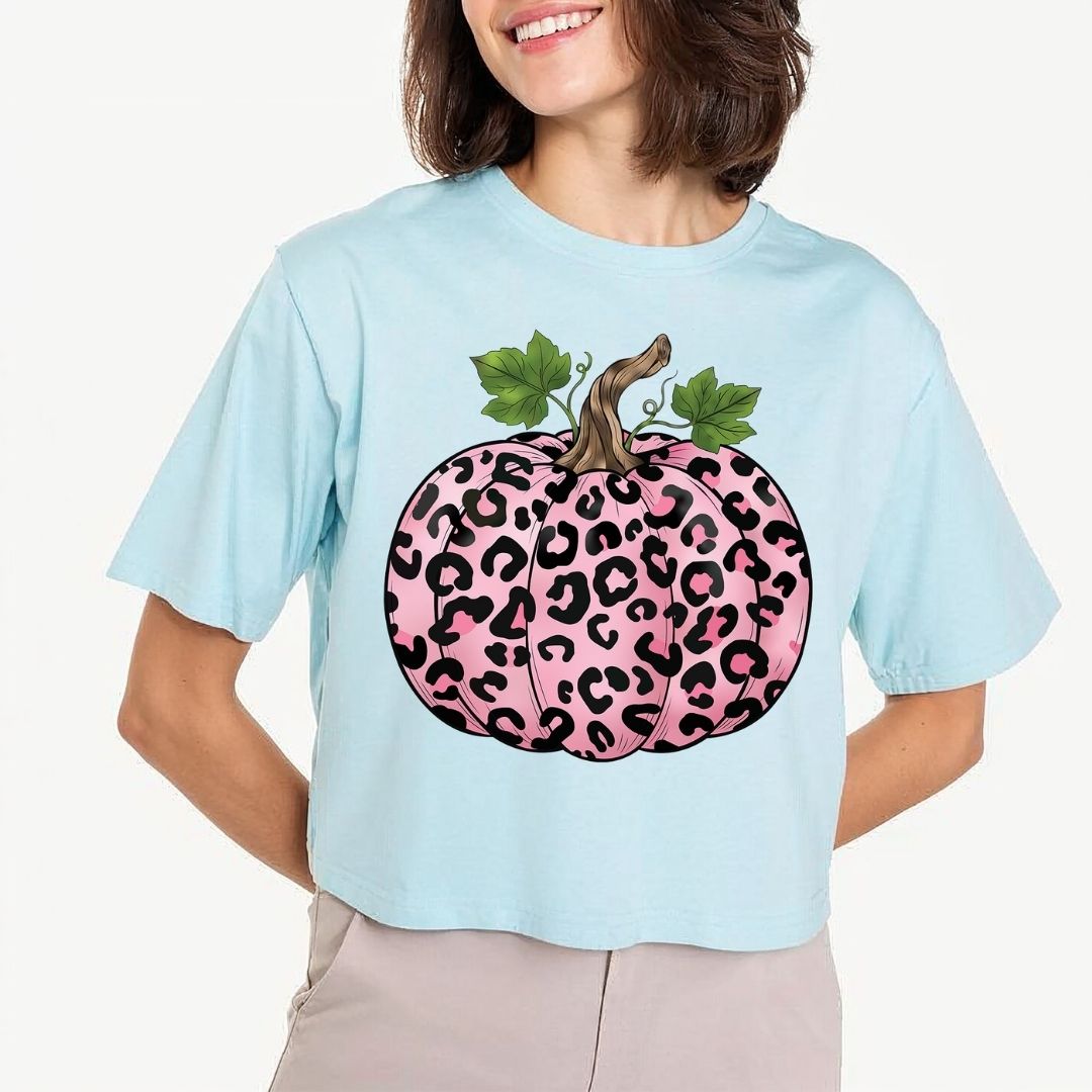 Person wearing a light blue t-shirt with a pink leopard print pumpkin design.
