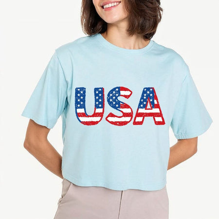 Person wearing a light blue t-shirt with 'USA' printed in American flag colors on a white background