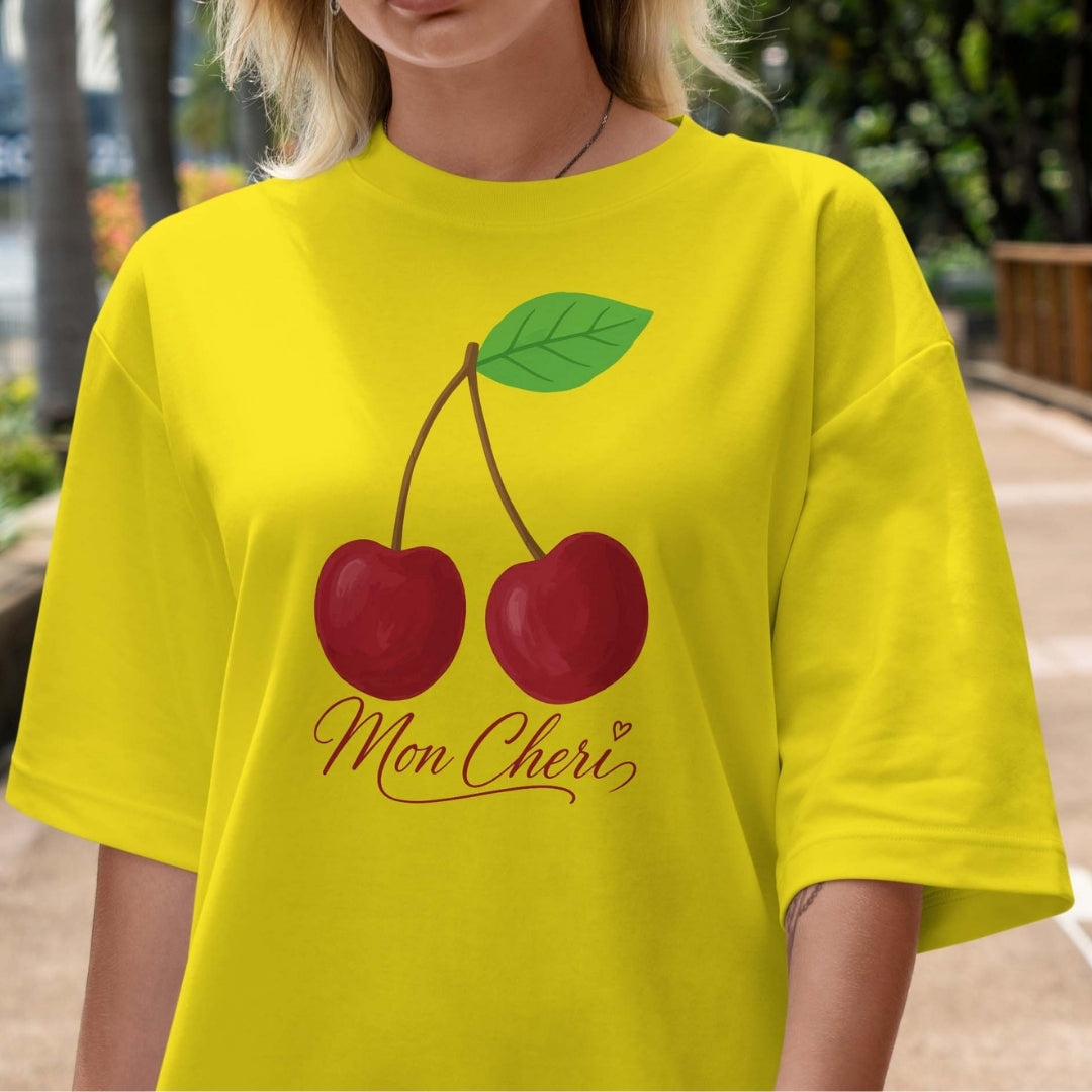 Person wearing a yellow t-shirt with cherry design and 'Mon Cheri' text.