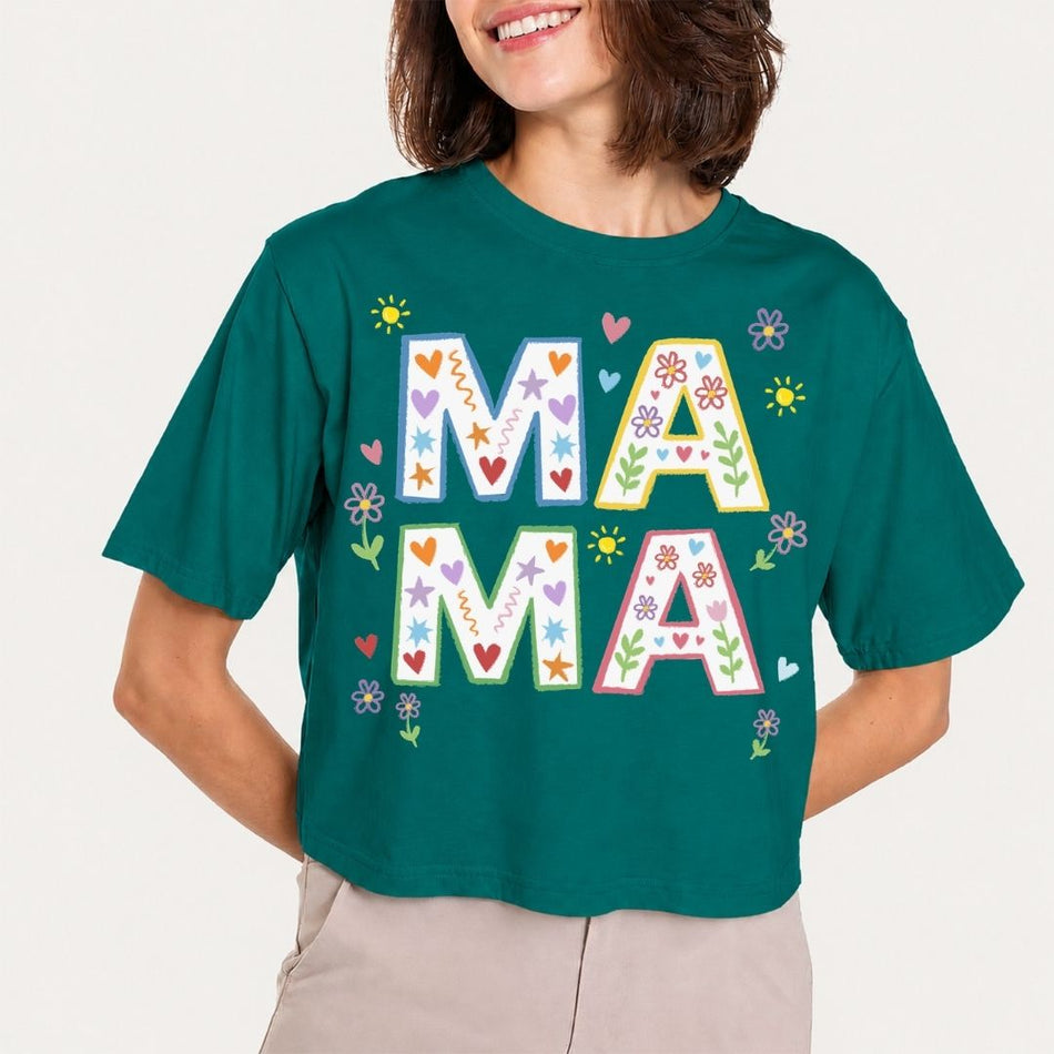 Person wearing a green t-shirt with 'MAMA' printed on it against a plain background
