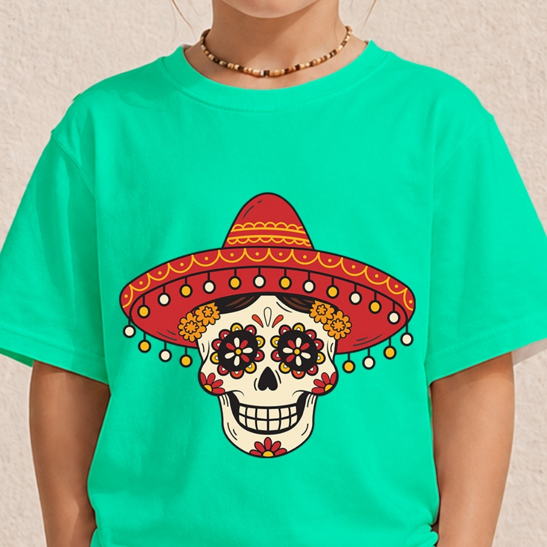A person wearing a bright turquoise T-shirt with a large Day of the Dead sugar skull graphic wearing a red sombrero on the front, against a light textured wall.