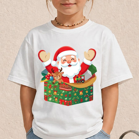 A child wearing a white short-sleeve T-shirt with a colorful Christmas graphic of Santa Claus popping out of a wrapped gift box, against a light beige textured wall.