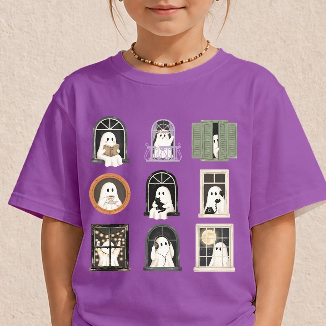 A child wearing a purple short-sleeve t-shirt with a graphic of nine cute cartoon ghosts in various window poses, set against a textured beige wall.