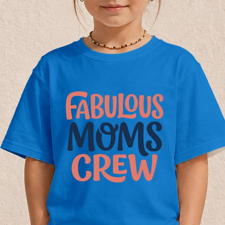A child wearing a bright blue graphic T-shirt with the words 'FABULOUS MOMS CREW' printed in coral and dark navy lettering, against a light textured wall.