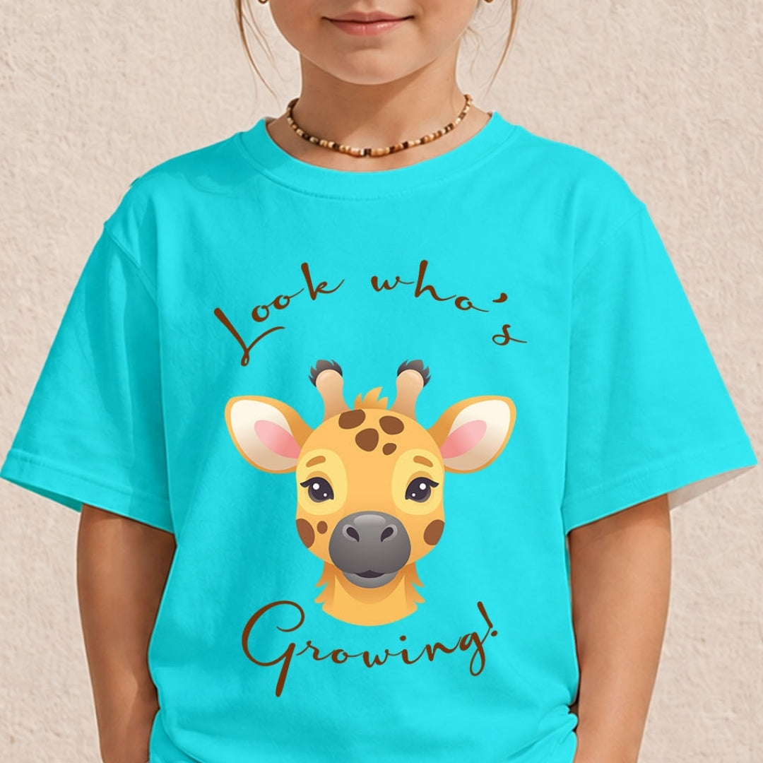 Young child wearing a bright cyan blue t-shirt with a cute giraffe face illustration and text saying Look Whos Growing.