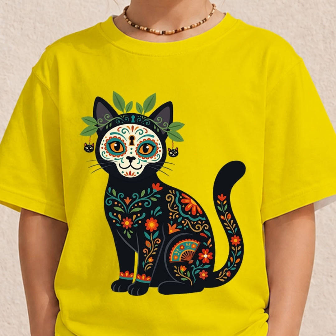 Close-up of a child wearing a bright yellow crewneck t-shirt featuring a stylized black cat illustration with Mexican floral sugar skull decorations.