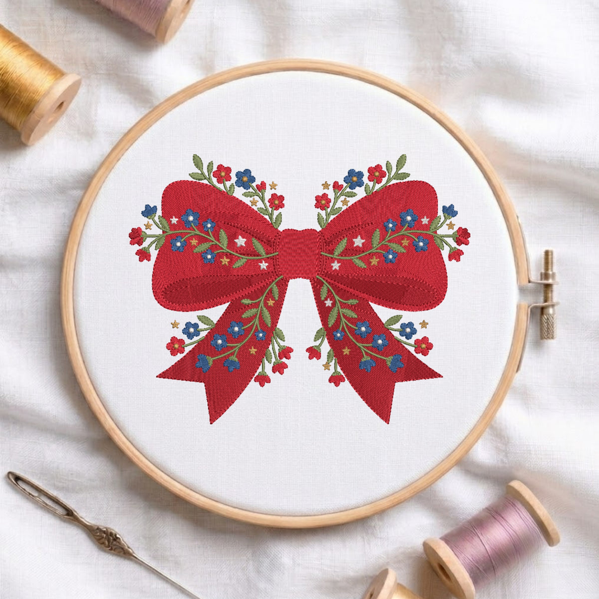 Red ribbon bow embroidery design detailed with blue and red floral embroidery stitches inside a wooden hoop.