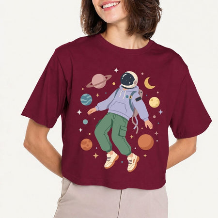 Person wearing a maroon t-shirt with an astronaut graphic on a plain background