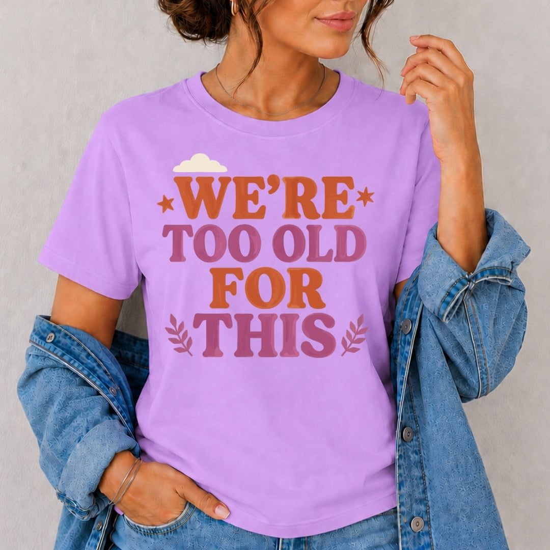 Person wearing a purple t-shirt with text 'WE'RE TOO OLD FOR THIS' against a plain background
