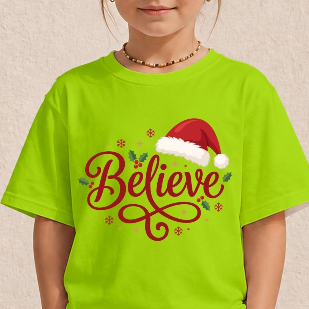 Child wearing a neon green t-shirt featuring a festive "Believe" typography design with a Santa hat.