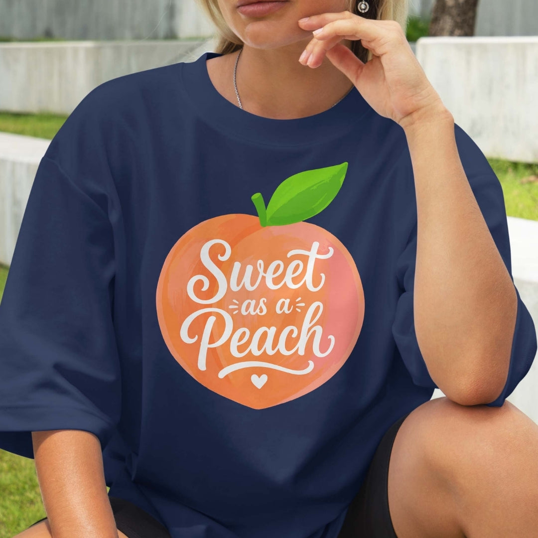 Person wearing a navy blue t-shirt with a peach graphic and 'Sweet as a Peach' text.