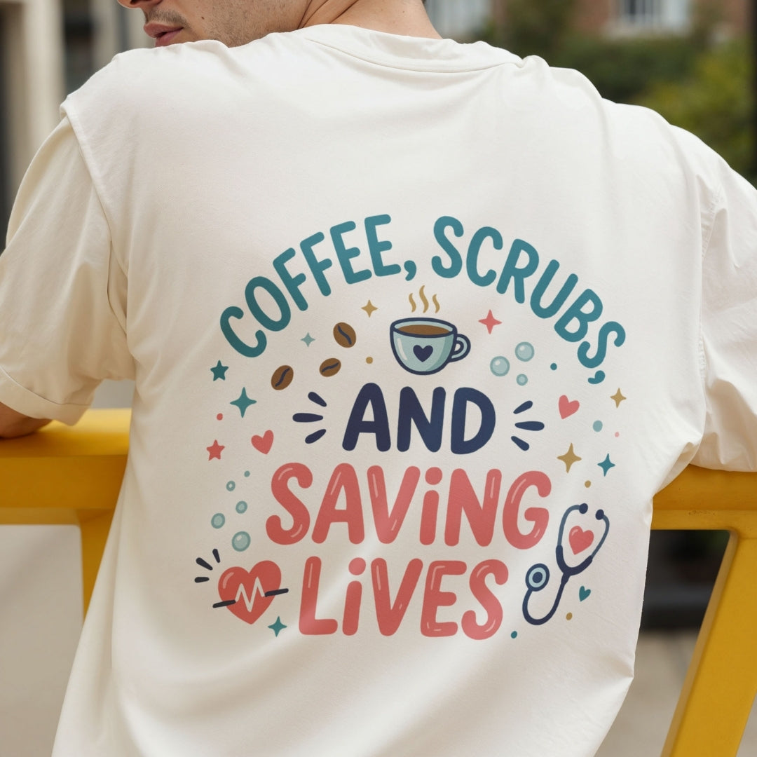 A man wearing a cream-colored t-shirt from the back, featuring a colorful graphic print that reads 'COFFEE, SCRUBS AND SAVING LIVES' with coffee beans, a coffee cup, a stethoscope, and hearts.