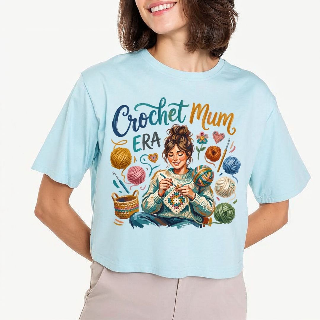 Person wearing a light blue t-shirt with 'Crochet Mum Era' design.