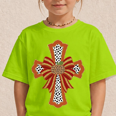 A child wearing a bright lime green t-shirt with a large decorative cross graphic on the front. The graphic features red and orange ribbon bows, leopard print details, and gold glitter accents.