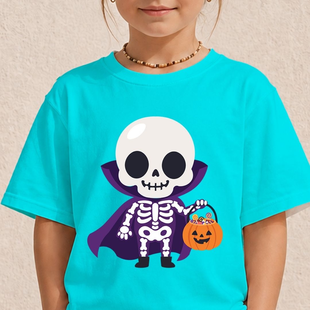 A child wearing a bright turquoise short-sleeve T-shirt with a cartoon skeleton in a purple cape holding an orange pumpkin bucket. The child is cropped from the mouth down, wearing a beaded necklace, against a light beige textured wall.