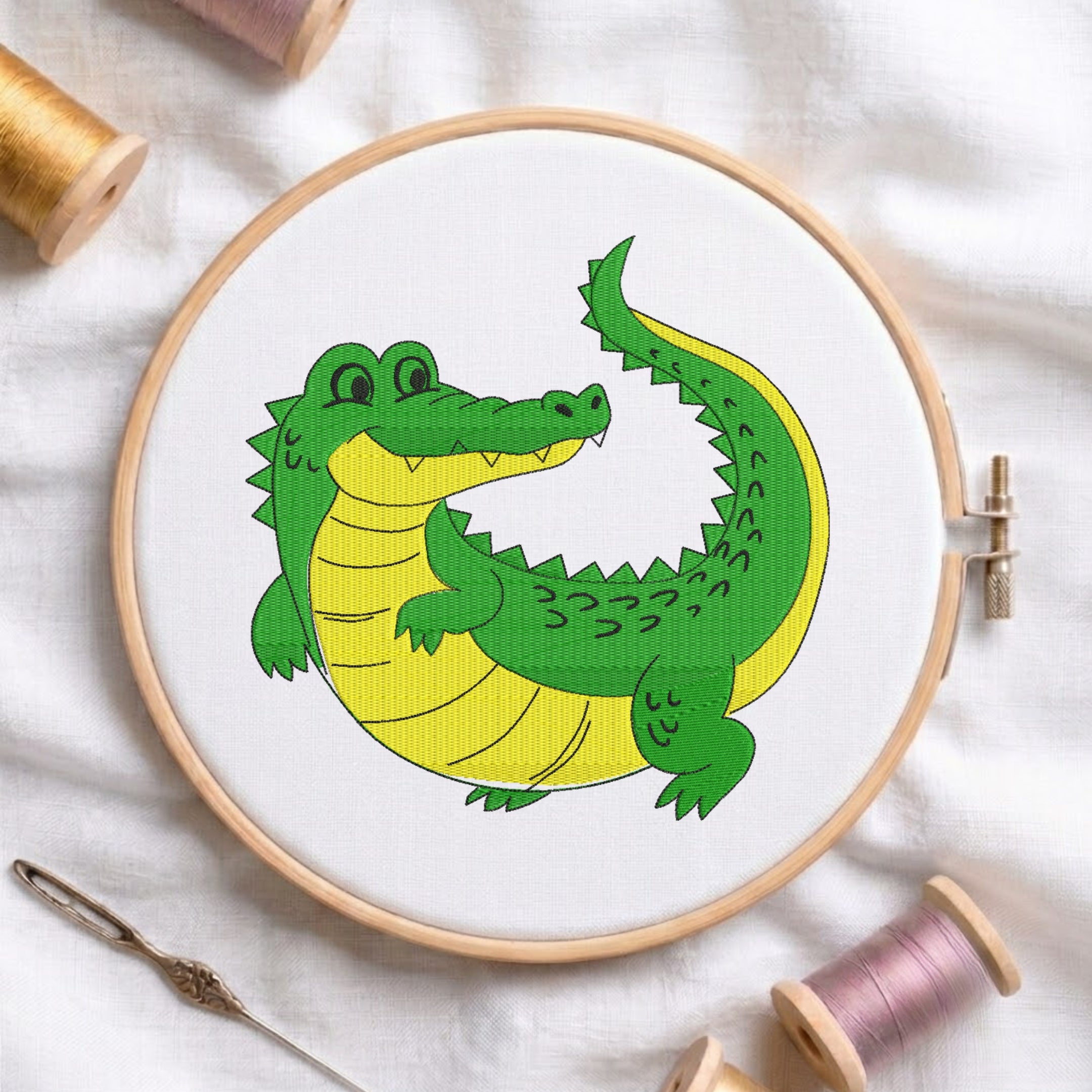 Cute green and yellow alligator embroidery design framed inside a wooden embroidery hoop.